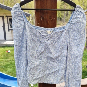 Blommig blus - Sockersöt somrig blus med smock. Bra passform. Rek stl 38.  Obs varan ligger ute på ett annat ställe, först till kvarn.
