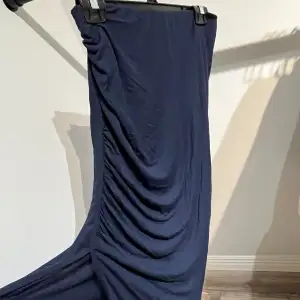 Marinblå kjol med skrynkligt på sidan och en slits.