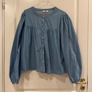 Jeans blus med vita knappar - Jeansklädda med vita knappar. Storlek 44 för lite oversized effekt, (har normalt M 38/40 i toppar). Nyskick. Luftig och tunn material.