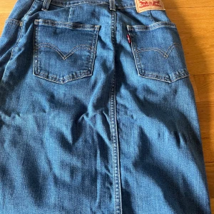 Jeanskjol från Levi’s - Bra skick. Knäppes fram. HLvlång modell med knappar framtill.