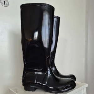 Svarta gummistövlar  - Helt oanvända gummistövlar i gott skick som legat bortglömda i förrådet. Endast använda inomhus när de var nyköpta. Storlek 38. Högt skaft. Lite smalare passform. 