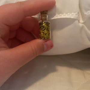 Guldglittrig ögonskugga i flaska - En liten flaska med guldglittrig ögonskugga. Perfekt för att lägga till en glittrande touch till din makeup.