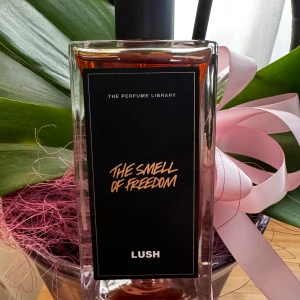 The Smell of Freedom - En parfym från Lush med namnet 'The Smell of Freedom'. Den är handblandad med fina eteriska oljor och innehåller ingredienser som sandelträ, oudh och citrongräs. Doften är rik och jordig med en rökig ton, vilket gör den både lockande och djup. Flaskan är genomskinlig med en svart etikett och rymmer 100 ml.