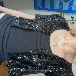 Svart paljettväst - En svart bolero täckt med paljetter. Västen är ärmlös och har en glittrig yta som passar perfekt för festliga tillfällen.💕💕💕Hör av er med frågor och tryck gärna köp nu!