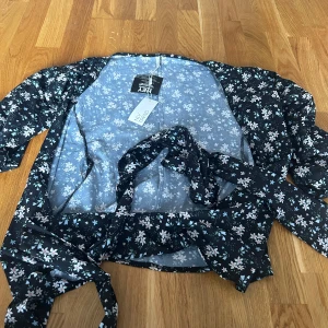 Blus från nelly - Blommig blus från Nelly som man knyter runt höfterna/ magen. Helt ny. Aldrig använd.