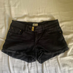 Lågmidjade shorts - Säljer dessa svarta vintage lågmidjade jeansshorts från Gina tricot i strl 36/S❤️De har jättesöta små hjärtan på alla guld detaljer🤩Midja rakt över:38cm, Längd:24cm, Grenhöjd:19,5cm, Lårbredd:23cm🙌🏻Har strecht. Tyvärr för stora för mig därav till salu🥲