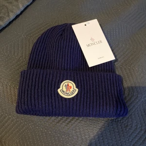 Moncler mössa - Moncler mössa i mörkblå, skick 10/10 helt ny