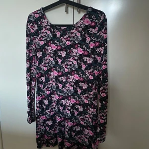 Blommig klänning med v-ringad rygg - En blommig långärmad klänning med en djup v-ringning i ryggen😊 går ungefär ner till lite över knäna på mig som är 1.60 cm.
