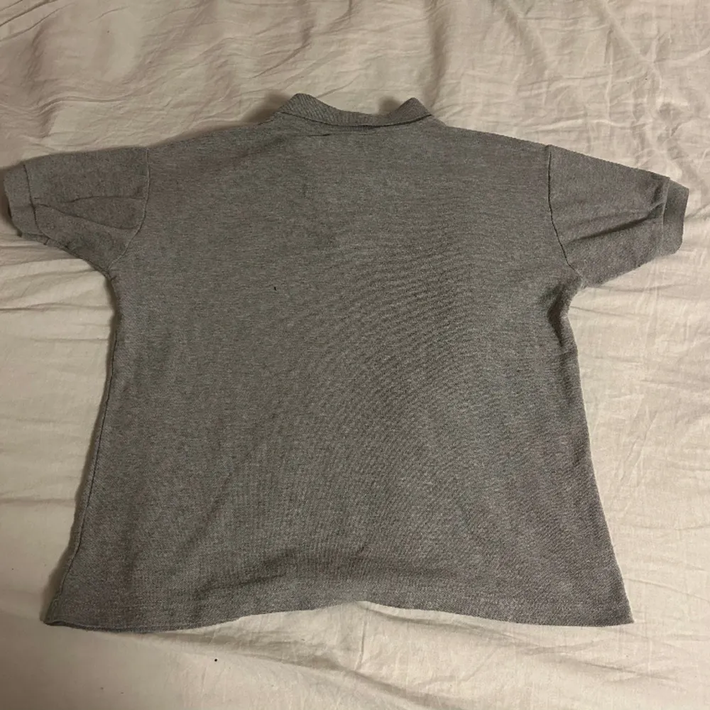 Säljer en Lacoste pike i storlek S. Knappt använd, i grå.. T-shirts.