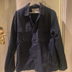 Overshirt - Säljer denna Overshirt som är perfekt till våren, Storleken är M och den är mörk blå i färgen. Den kommer från A Days March och ligger på 1100 nypris, knappast använd och iprincip helt ny. Hör av er vid frågor, pris ej hugget i sten🧱🗡️