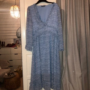 Mönstrad blå långklänning  - Ankellång mönstrad blå klänning med ärmar. Sitter väldigt fint på, bra skick.