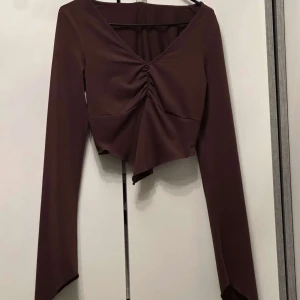 Crop top - Oanvänd brun crop topp från nelly. Toppen har utsvängda ärmar.