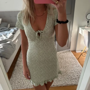 Grön kortklänning med blommigt mönster - En grön kortklänning med blommigt mönster. 