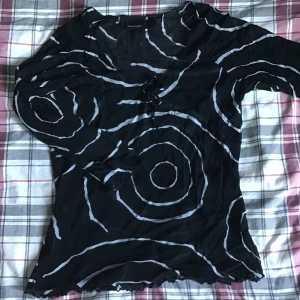 Mesh topp - Svart vit mönstrad Mesh topp från Kappahl, med knyt på framsidan och volanger vid ändorna. Tröjan har använts väldigt få gånger och är i väldigt bra skick.