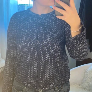 Marinblå blus  - En marinblå blus med vitt mönster. Märket är Kaffe, storlek 36. Mjukt och tunt material.