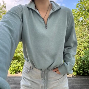 Tröja med zip och justerbar midja - Turkos/blå/aqua färgad, långärmad tröja med zip samt justerbar midja från American Eagle. Går att bära på olika sätt, se bilderna. Storlek: M. Material: 60% bomull + 40% polyester. :)