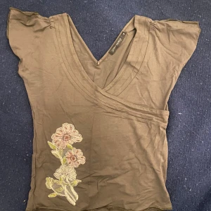 Fin vintage T-shirt med broderi - Säljer denna superfina topp i khaki färg med unika detaljer från Saint Tropez. Den är i bra skick och har inga defekter alls. Passar xs/s/m