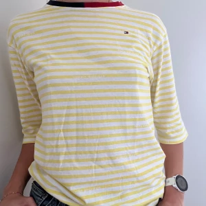Gulranding T-shirt från Tommy Hilfiger - Gulrandig T-shirt i storlek 176/ M med marinblå och röd krage i gott skick. 