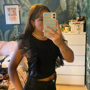 Svart festtopp - Så fin svart festtopp med stora volanger längst med sidan av toppen. Nyskick, Right och kort i magen. 