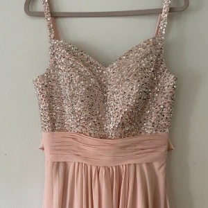 Balklänning - Ljus rosa balklänning med silver paljetter och satinrosett på ryggen.  Storlek är ca S/M 36/38. Smalaste del på midjan är 74cm och klänningen är 155cm lång från axeln ner till. 