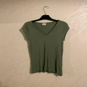 Grön t-shirt Vila - Grön t-shirt från Vila. Använd en gång. Blivit ett litet hål i halsen (se bild). 