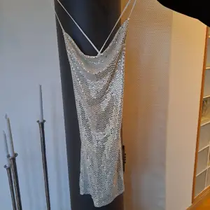 Glittrig klänning från hm, oanvänd med prislappen kvar. Väldigt fin med öppen rygg och snörning Storlek xs Frakt tillkommer
