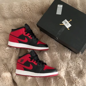 JORDAN 1 MID - Säljer mina Jordan 1 mid i röd/svart. Använda ca 2 gånger, helt nya. Kartong medföljer. Storlek 38,5 passar på normal 38. Säljer för 1100 kr. 