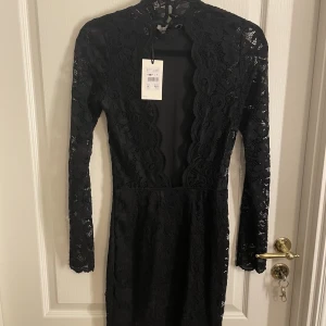 Spetsklänning med öppen rygg - Klänningen är bodycon och har en lite högre krage. Aldrig använd och har prislappen kvar, stl S. Skriv om ni har frågor 💗