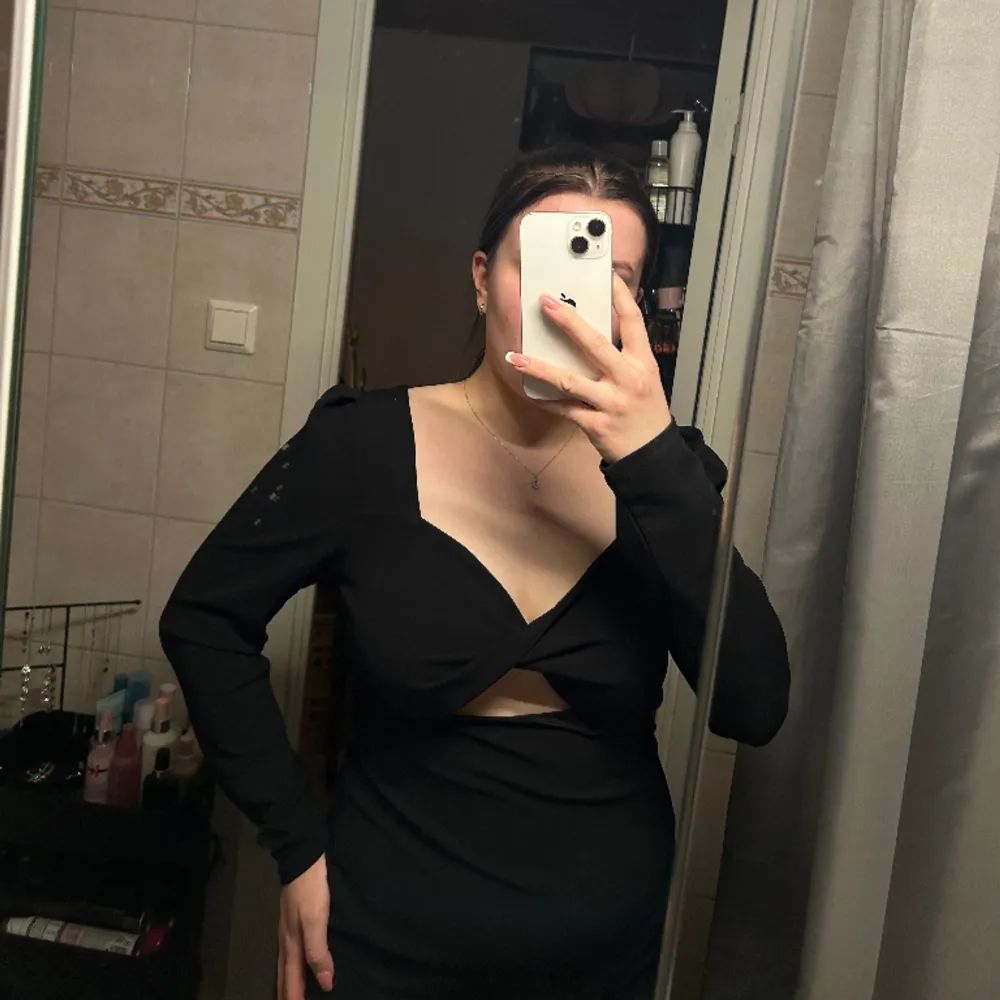En svart klänning med detalj över bröstet.. Klänningar.