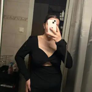 En svart klänning med detalj över bröstet.