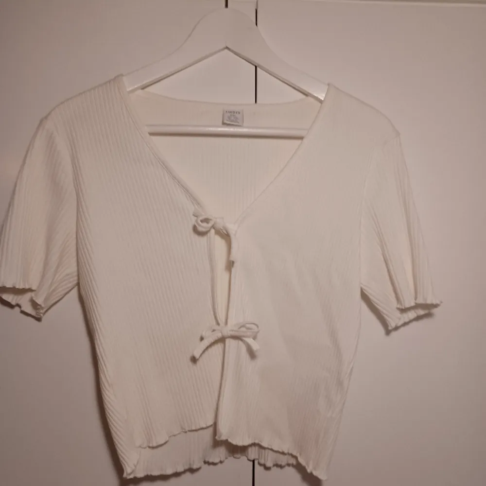 Säljer denna cream vita ribbade t-shirt koftan i nyskick som man kan knyta i mitten✨️Säljer denna för 59 kornor och är köpt för 200🎀. Tröjor & Koftor.