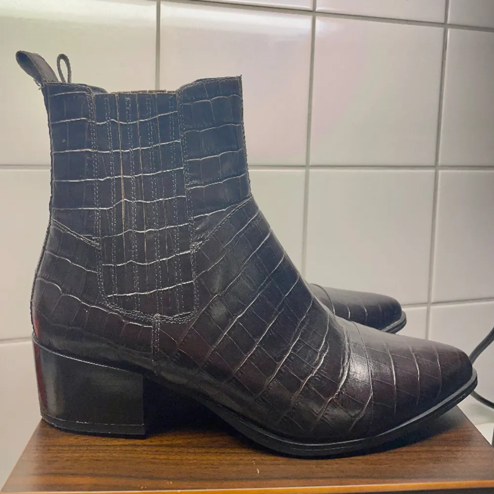 Vagabond cowboyboots i modellen Marja. Ankelhöga i brun färg med krokodilmönster i läder , spetsig tå. Storlek 42. (Upplevs små i storlek , vanligtvis storlek 41). Inget att anmärka på , använda vid 2 tillfällen.. Skor.