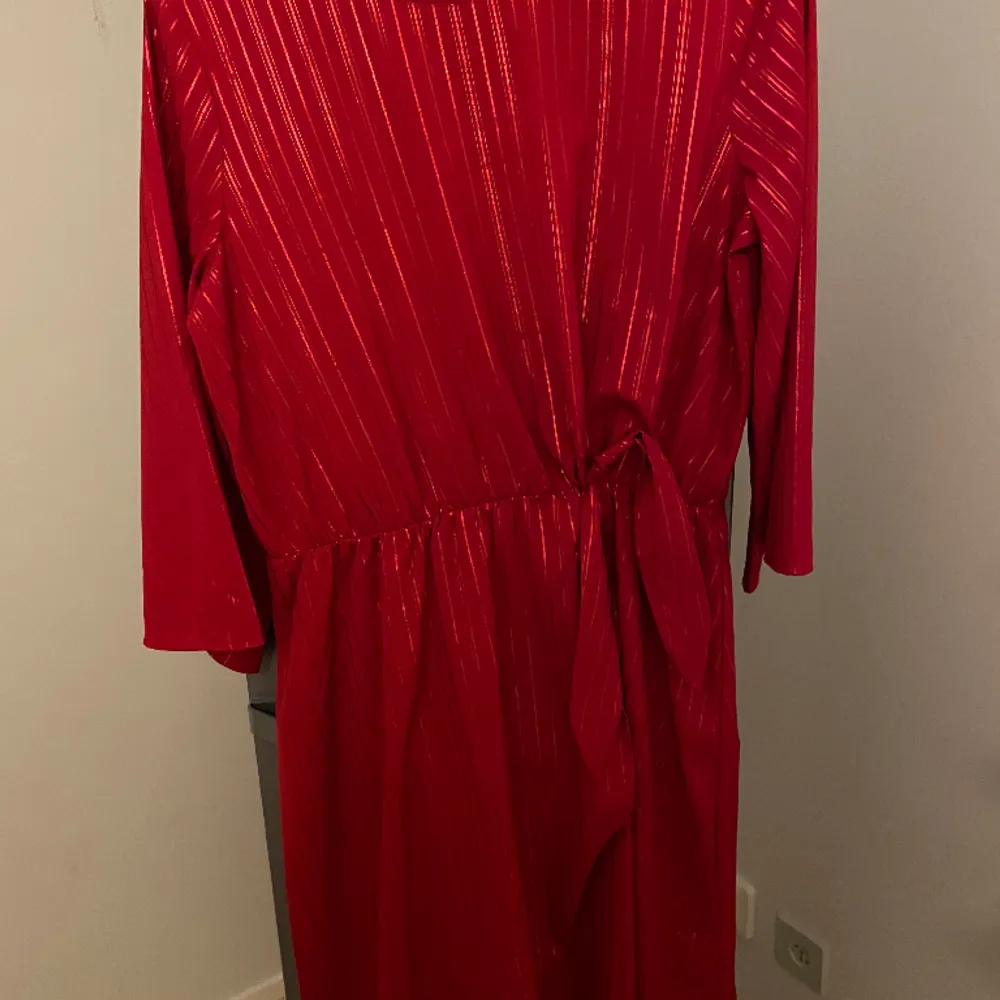 Röd klänning med resår i midjan för skurningen. Omlott klänning med en dekorknut på sidan.  Från Lindex i storlek 170. Klänningar.