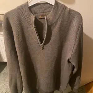 En stilren Lite ljusgrön/grå halfzip tröja från det attraktiva märket Stenström. Skicket på tröjan är 8/10 då den är använd men utan någon stölre deffekt. Storlek L/Xl.