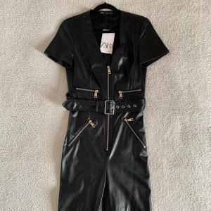 ZARA Limited Edition svart PU läder jumpsuit - SUPERsnygg jumpsuit i PU skinn från ZARAs Limited Edition kollektion. Dragkedja vid bysten och skärp. Slits med dragkedja vid fötterna och bekvämt och mysigt material/foder på insidan. Sitter som ett smäck. Ny med tags kvar.