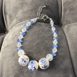 Handgjort pärlarmband med blåa, blå-vita och genomskinliga pärlor och med silvrigt spänne. Justerbar passform mellan 19-24 cm.