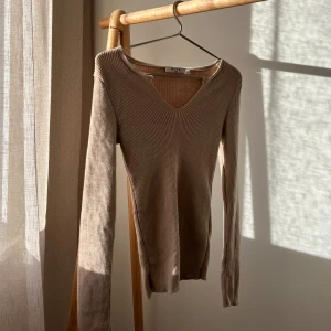 Tröja - Tight ribbad tröja med v-detalj i bra skick, storlek xs men passar s också. Mörk beige färg.