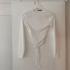 Tröja boohoo - Vit långärmad tröja från boohoo med helt öppen rygg och knytning längst ner. Stl 38 men passar även 36 34.
