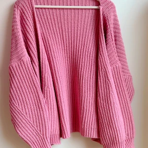 Rosa stickad kofta - Rosa, stickad kofta från Missguided. Köpt på Nelly år 2021.  Storlek 34/36.  Perfekt på våren eller under en sval sommarkväll.  Använd relativt mycket men i bra skick.  Material: 100% akryl. 