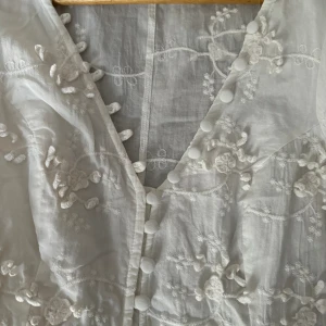 Fin klänning  - St xs/s puffärmar,3D-blommor,fina knappar.Använd 1 gång.Finns på flera sidor