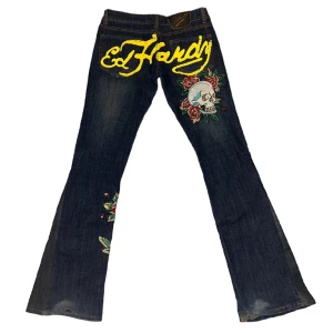 Ed Hardy jeans - Nyskick förutom längst ner på benet där bak det är lite slitningar (se bild 1). Har sytt ut de till bootcut. Midja rakt över: 38cm Innerbenslängd: 84cm Skriv vid fler bilder eller frågor💕