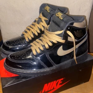 JORDAN 1 "BLACK METALLIC GOLD" High  - Säljer ett par JORDAN 1 "BLACK METALLIC GOLD" Hugh i storlek 43. Skorna är endast testade , då dem är i nyskick. Extra snören medföljer.  Finns i Motala eller spårbarfrakt:) 