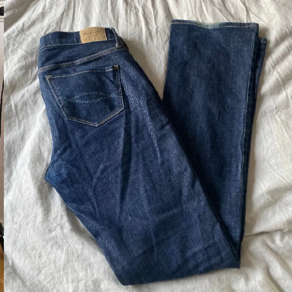 Mörkblå lågmidjade jeans med snygga detaljer på fickorna. Snyggt bootcut. Midjemått 39 cm rakt över. Innerbenslängd 80 cm. Jag är 163 cm på bilderna. Lite slitna längst ned se första bilden. Kan skicka fler bilder privat. Jeans & Byxor.