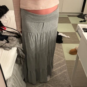 Grå långkjol - En söt långkjol med volanger. Köpt från Sellpy från början. På bilderna har jag vikt ner kanten för en mer lågmidjad look. Skulle säga att kjolen är en S/M
