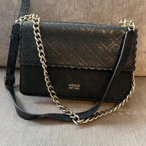 Guess väska  - Axelremsväska från Guess i silver med reglerbart band.  Använd men fortfarande i fint skick. 