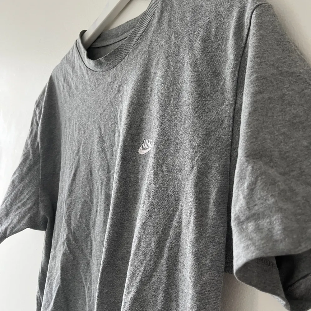 Unisex T-shirt från Nike. Grå och i använt skick. Storlek L. Nike-loggan är broderad. T-shirt i bomull. . T-shirts.