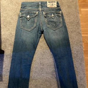 True religion jeans  - Jag säljer mina mörkblå true religion jeans i storlek 27 då dom är för stora för mig. Dom är i väldigt bra skick förutom små slitningar längst ner vid fötterna.