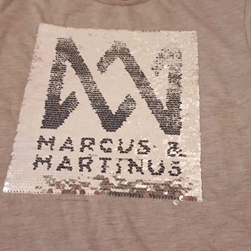 Det är en tröja med Marcus och Martinus på den går och bläddra till doms märke är en t-shirt. T-shirts.