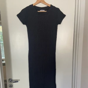 Midiklänning  - Figurnära ribbad midiklänning i en mörkgrå melange.  Mjukt och bekvämt material.  