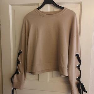 Tröja med snörning - Tröja med snördetaljer på ärmarna. Storlek L (44/46). Slutar typ precis under naveln på mig. 